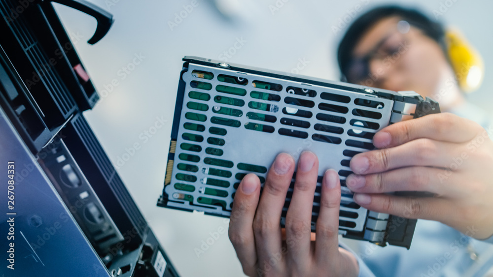 在数据中心：IT工程师在服务器机架设备中安装新的硬盘驱动器和其他硬件