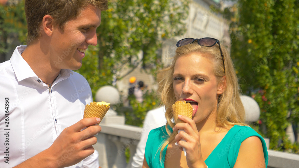 特写：一名年轻男子看着女友吃着美味的冰淇淋。
