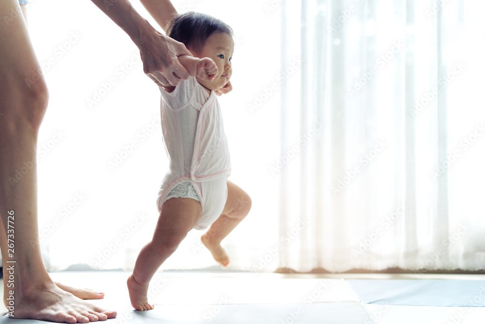亚洲宝宝迈出第一步，在柔软的垫子上向前走。快乐的小宝宝一起学习走路