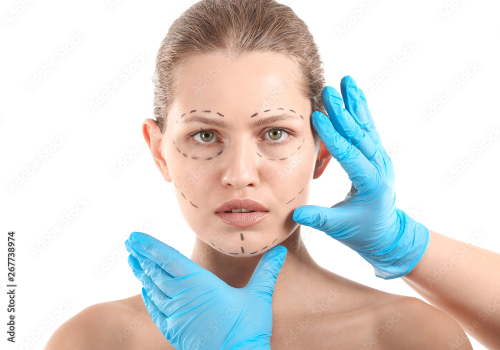 整形医生触摸年轻女子的脸，脸上有白色背景的痕迹