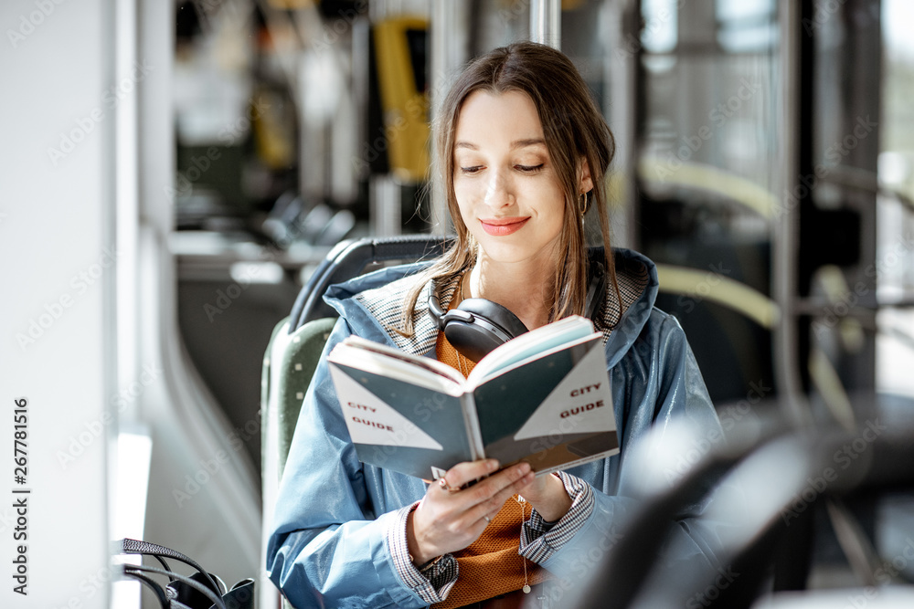 年轻女性在现代有轨电车上看书，公共交通工具上快乐的乘客