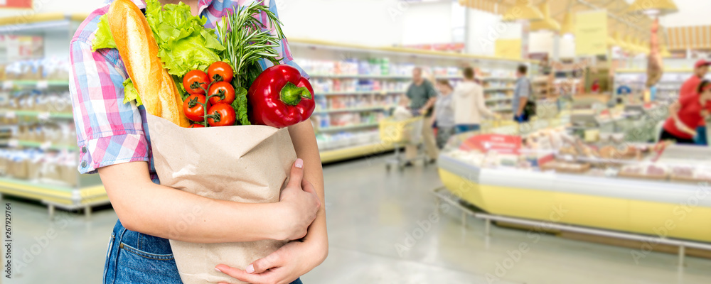 微笑快乐的女人在超市购物，把蔬菜装在环保袋里