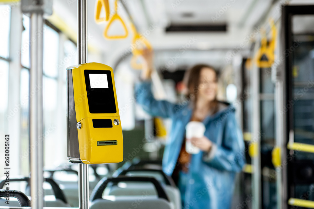 背景为女性乘客的现代有轨电车中的黄色售票机
