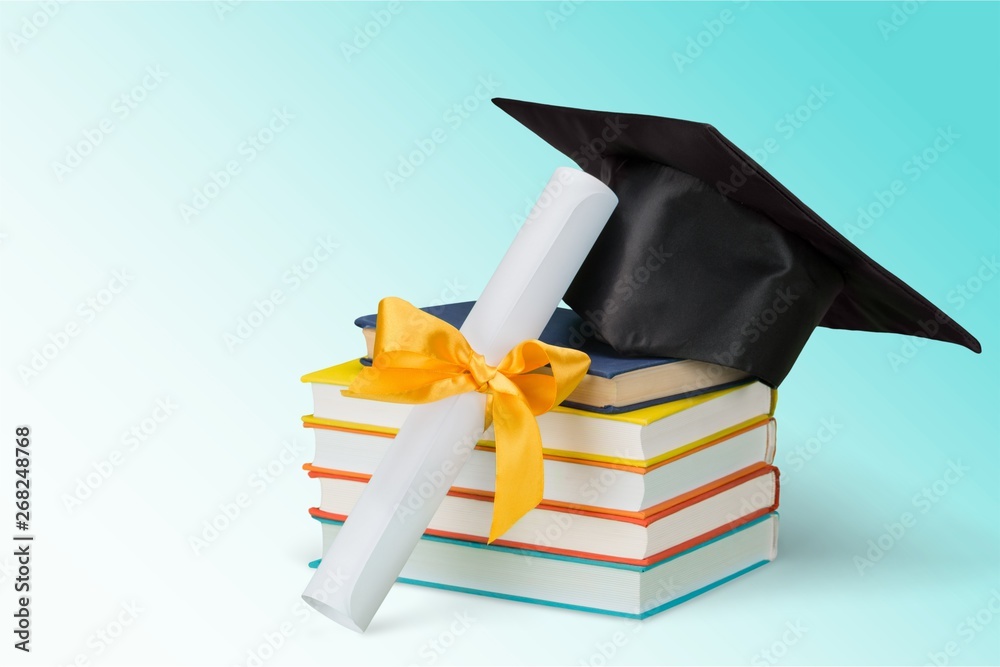 Graduation mortarboard on top of stack of books on  background
