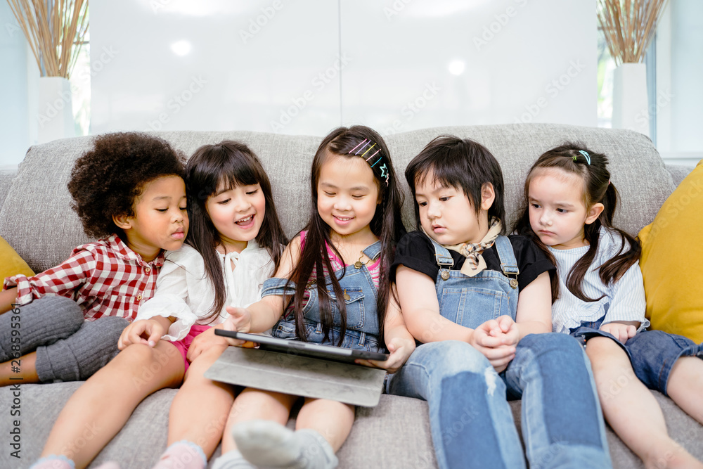 一群小孩子一起在数字平板电脑上看电影、电影和动画片。孩子们在玩t