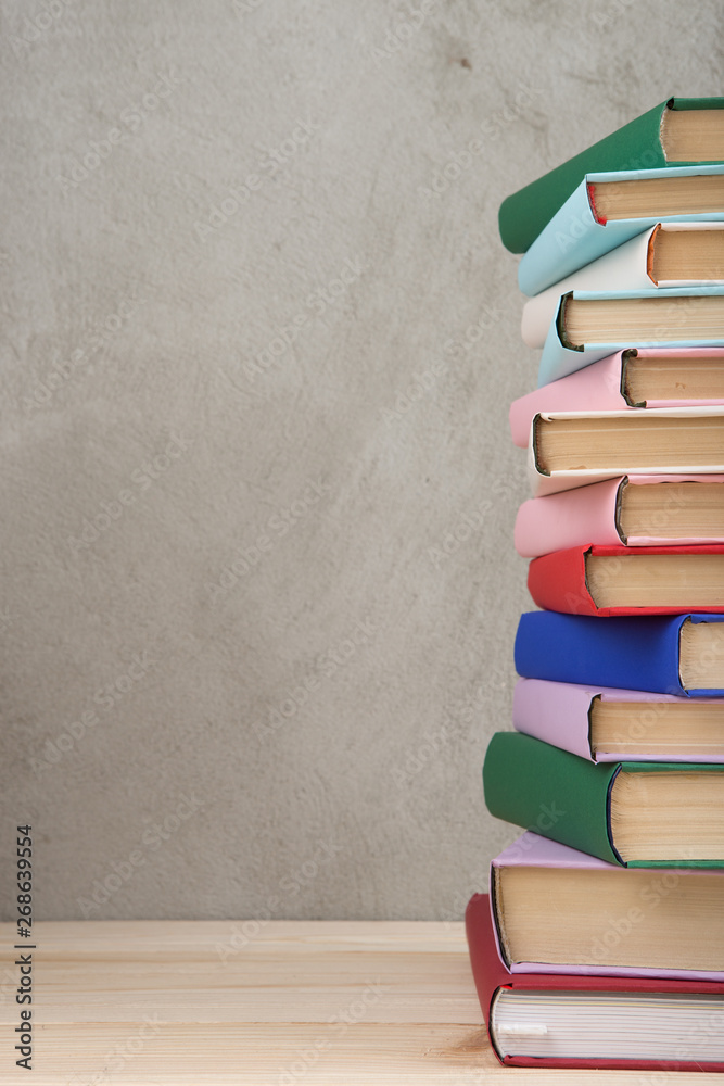 教育和阅读理念——木桌上的一组五颜六色的书，混凝土墙黑板