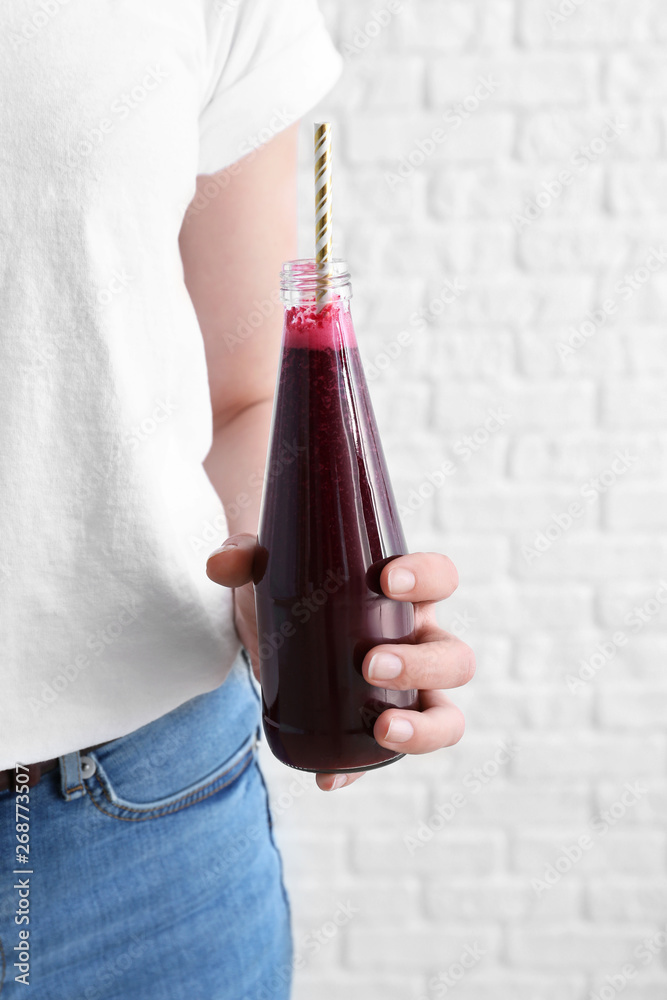 Woman with bottle of fresh beet smoothie on white background, closeup