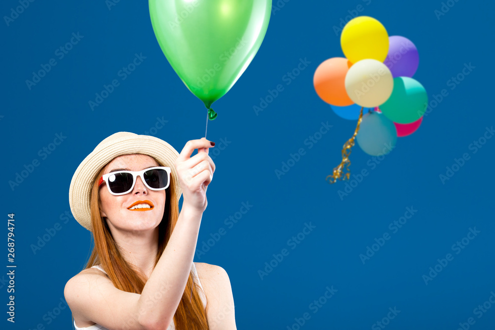 蓝天背景下拿着气球的年轻女子