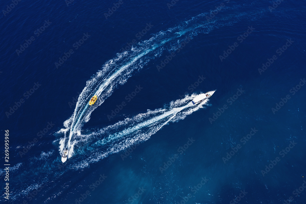 Yachts at the sea surface. Aerial view of luxury floating boat on transparent turquoise water at sun