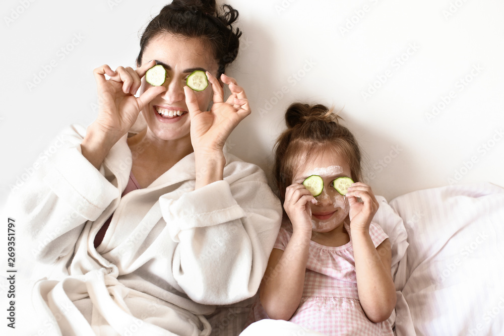 快乐的母亲和可爱的女儿在家护肤治疗期间玩得很开心