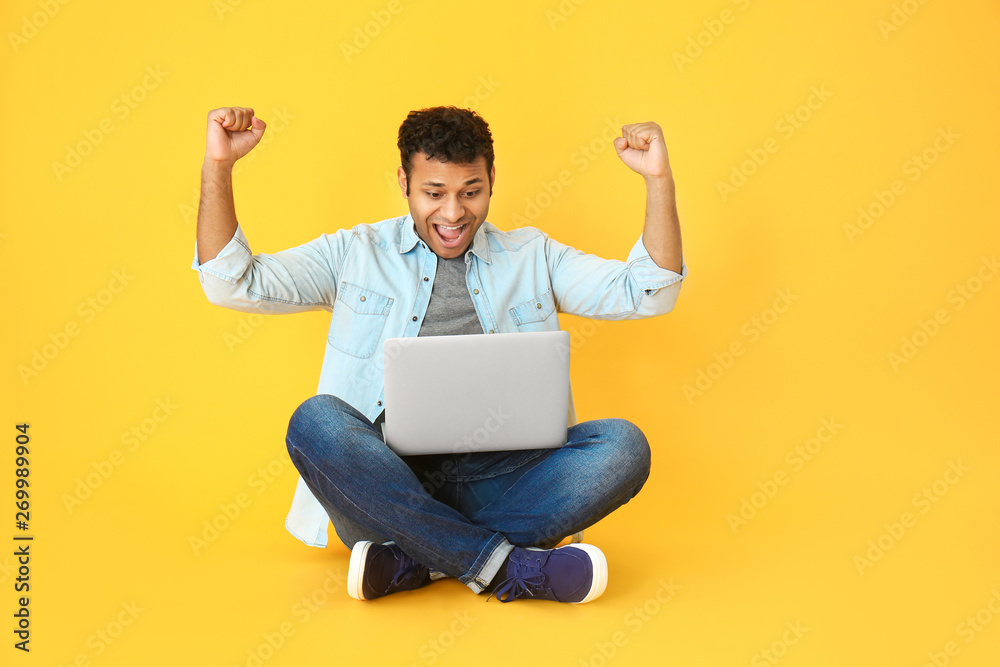 拥有彩色背景笔记本电脑的快乐男人