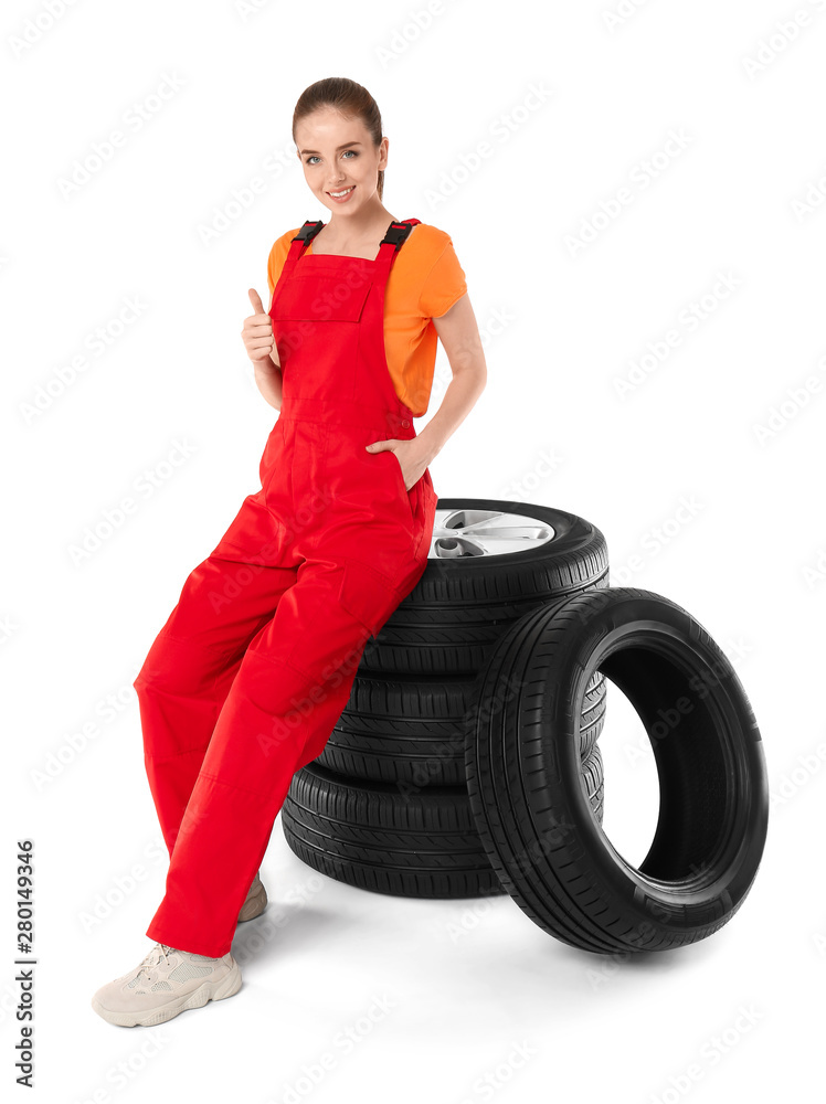 年轻的女机械师，穿着白色背景的汽车轮胎