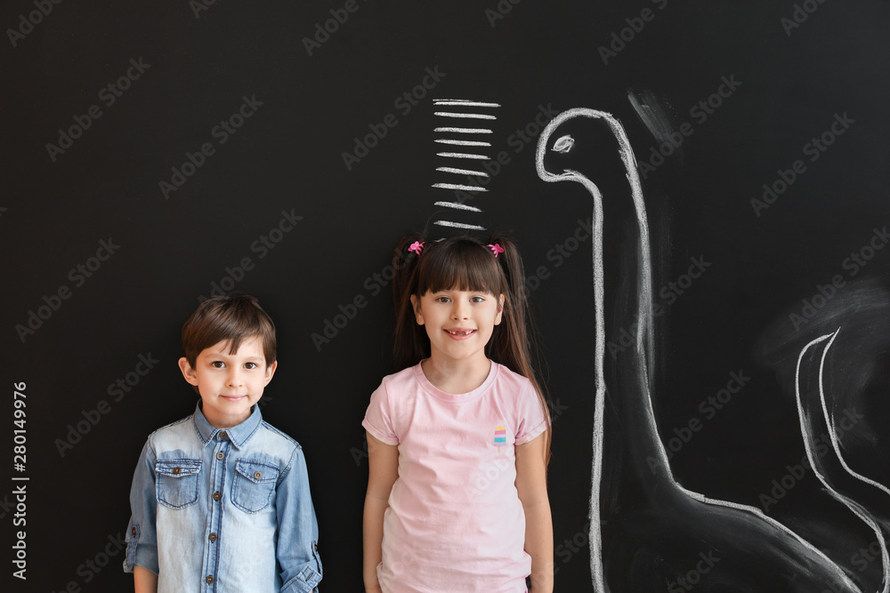 可爱的小孩在墙上用记号和画的恐龙测量身高