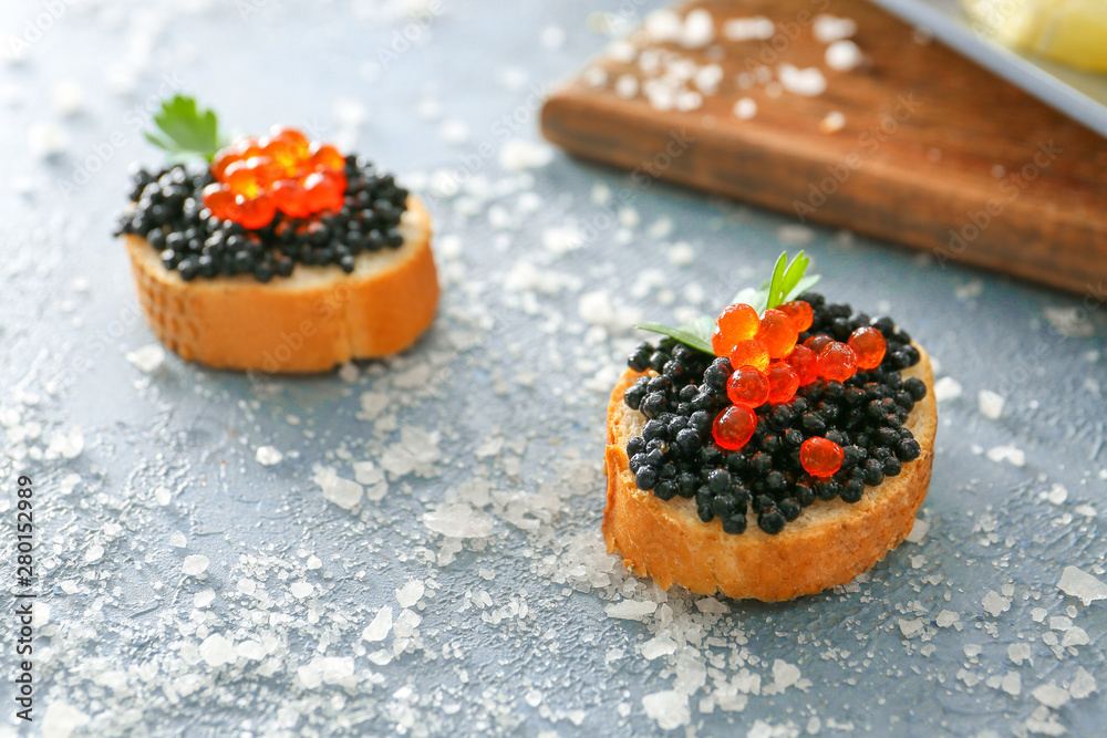 Sandwiches with black and red caviar on color background
