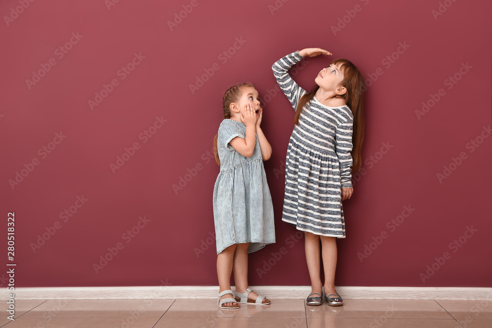 Little girls measuring height near wall