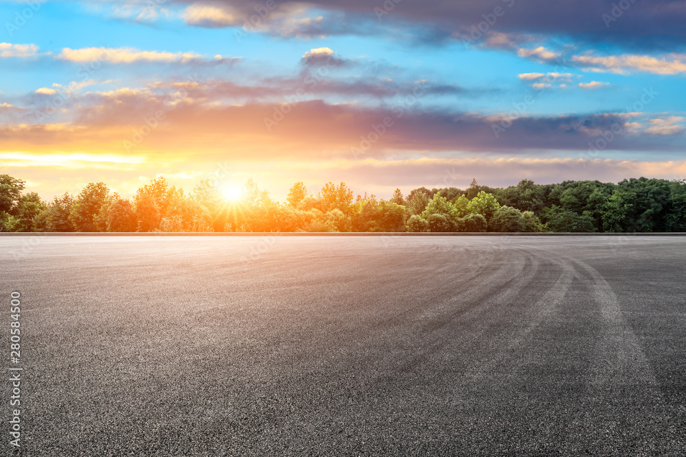 Asphalt race track and green forest with beautiful clouds at sunset