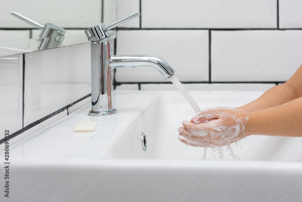 Kid washing hands in a white basin with a bar of white soap.