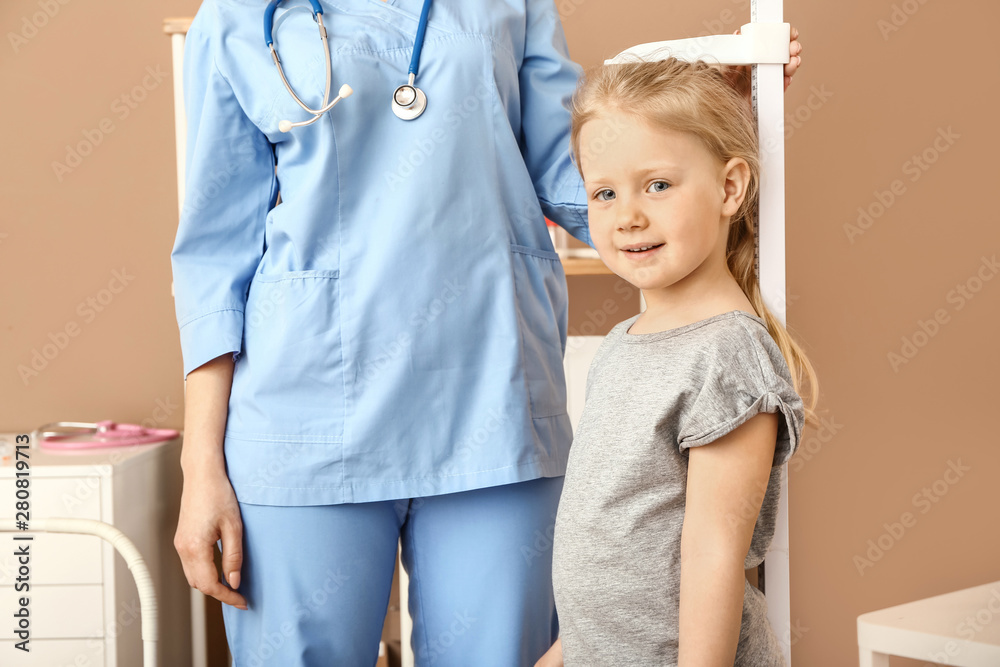 女护士在医院测量小女孩的身高