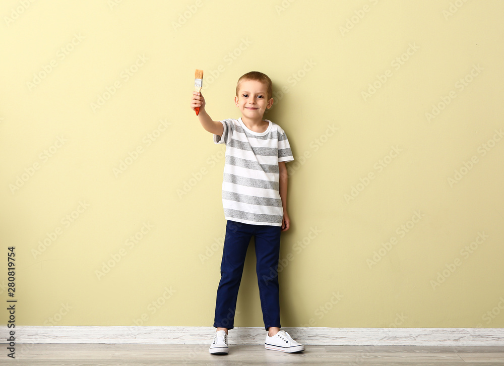 小男孩拿着画笔靠近彩色墙