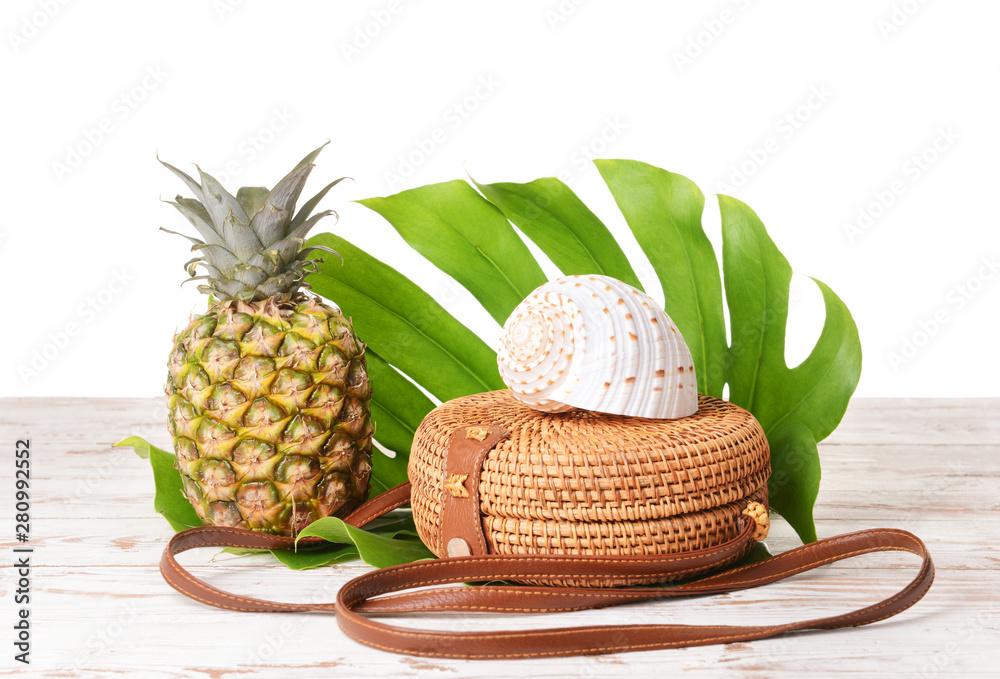 白色背景下桌子上的袋子、菠萝、贝壳和热带树叶