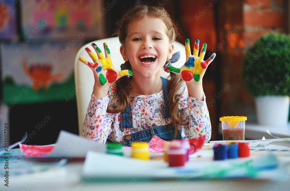 有趣的小女孩画画，笑得手被油漆弄脏。