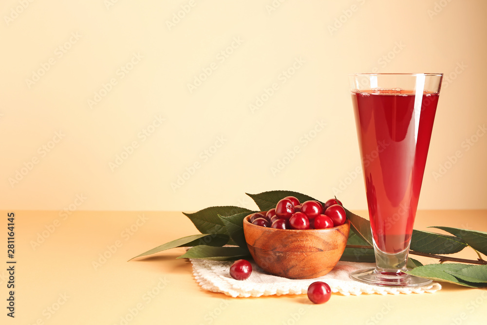 Glass of tasty cherry juice on color background