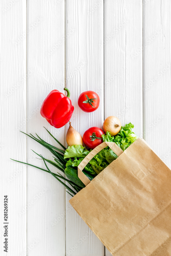 白色木质背景纸袋装新鲜蔬菜的健康食品俯视空间，用于文本
