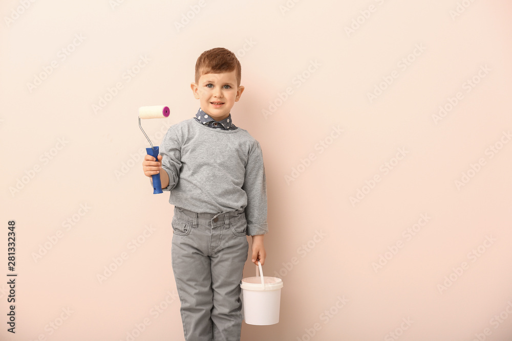 可爱的小男孩，彩色背景上有油漆滚筒和水桶