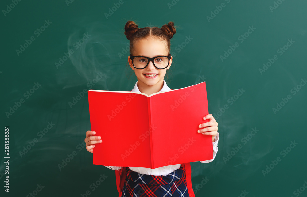 有趣的女学生，拿着一本关于学校黑板的书。