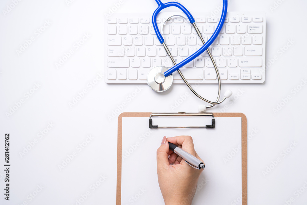 Female doctor writing a medical record case over clipboard on white working table with stethoscope, 