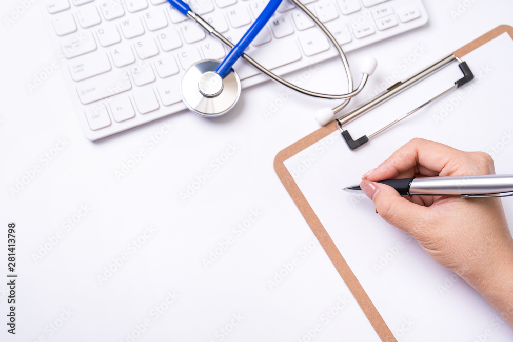 女医生用听诊器在白色工作台上的剪贴板上写病历病例，