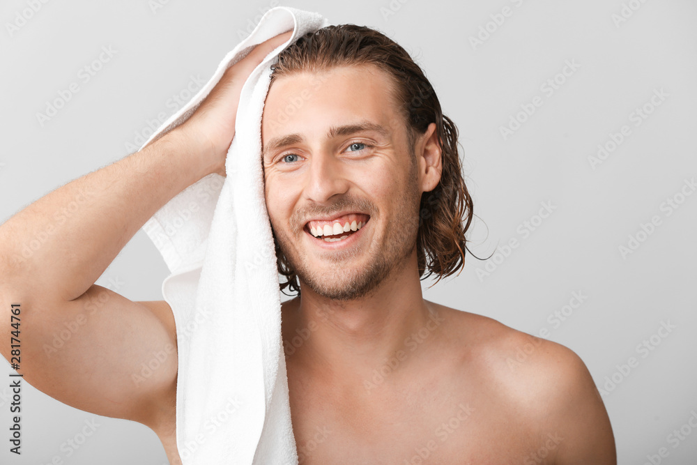 英俊男子在灰色背景下洗完头发后擦拭头发