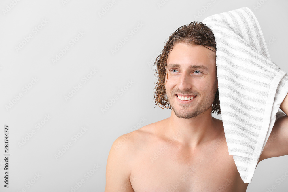 Handsome man wiping hair after washing against grey background
