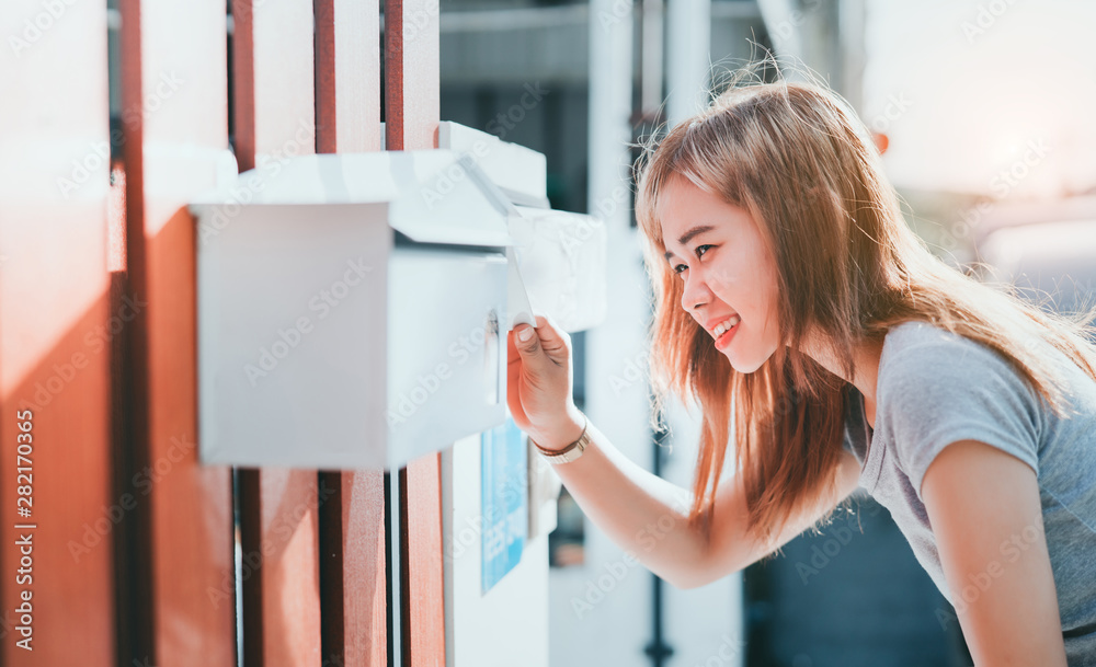 美丽的亚洲女人在家门口打开信箱检查，送货信息账单订单收到t