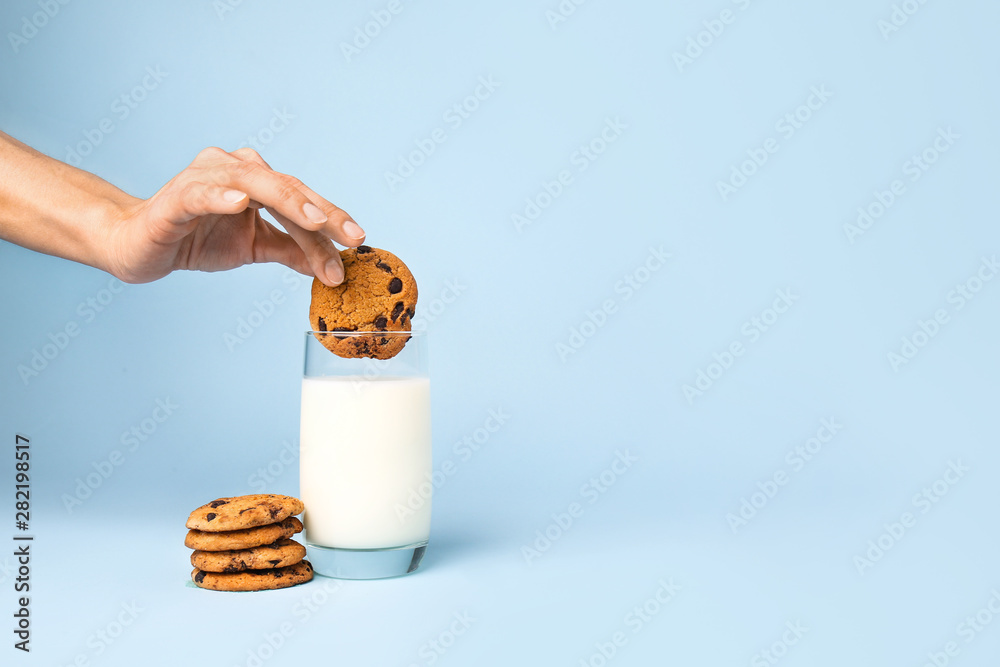 一位女士将美味的饼干蘸在彩色背景的牛奶中