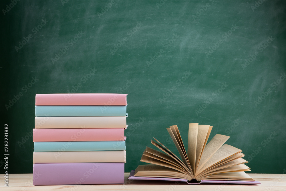 教育和阅读理念——教室木桌上的一组彩色书籍，黑板
