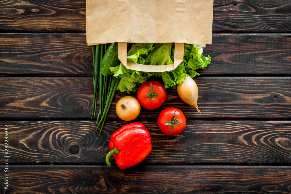 Healthy food with fresh vegetables in paper bag on wooden background top view