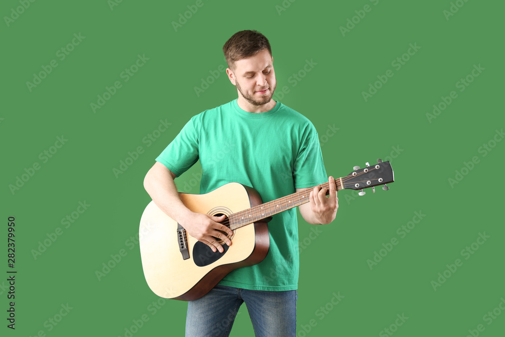 Handsome young man with guitar on color background