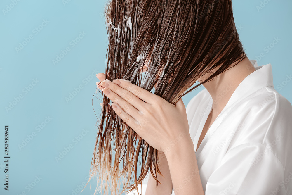 漂亮的年轻女人在洗完头发后在头发上涂慕斯，背景是彩色的