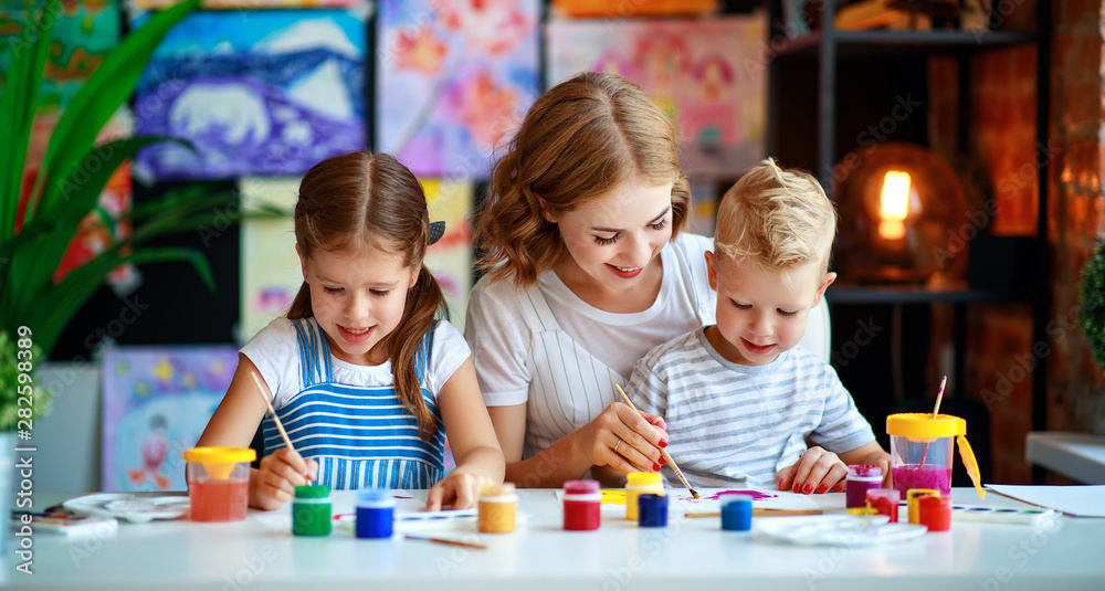 母亲和孩子的儿子和女儿在幼儿园绘画吸引创造力