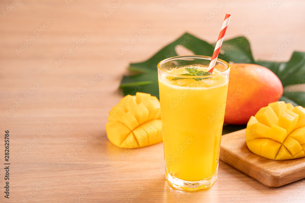 Fresh mango juice with beautiful chopped pulp flesh on bright wooden table background. Tropical frui