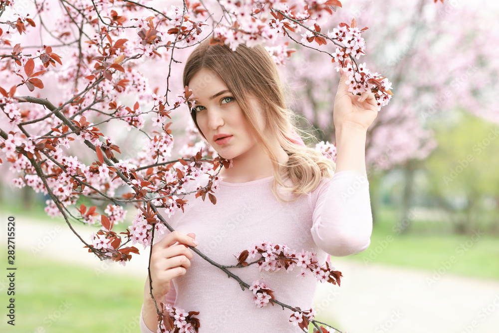 春日，美丽的年轻女子在开花的树旁