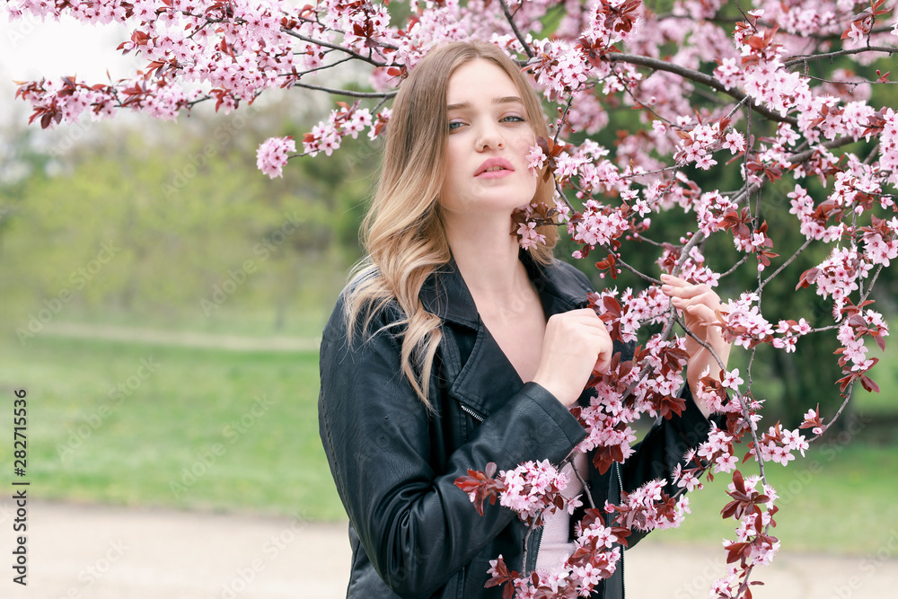 春日，美丽的年轻女子在开花的树旁