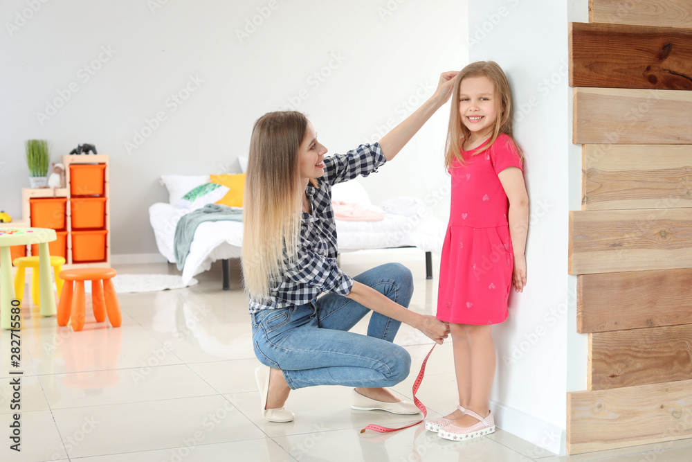 年轻母亲在家测量小女儿的身高