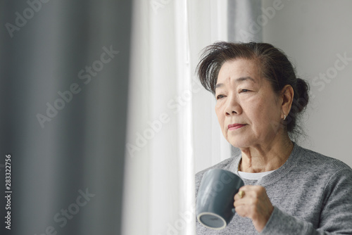 亚老女子在户外靠窗喝热茶，寂寞概念。