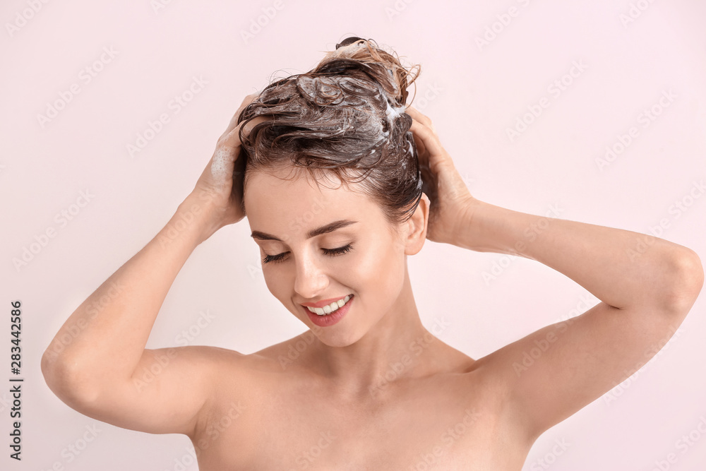 美丽的年轻女子在浅色背景下洗头