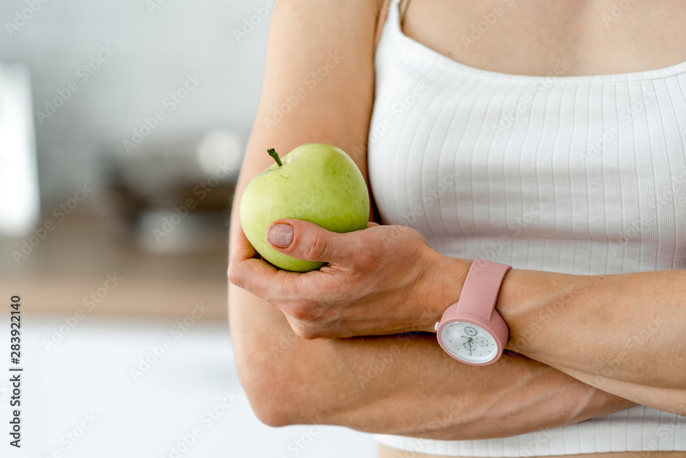 女人在厨房里吃苹果。均衡饮食