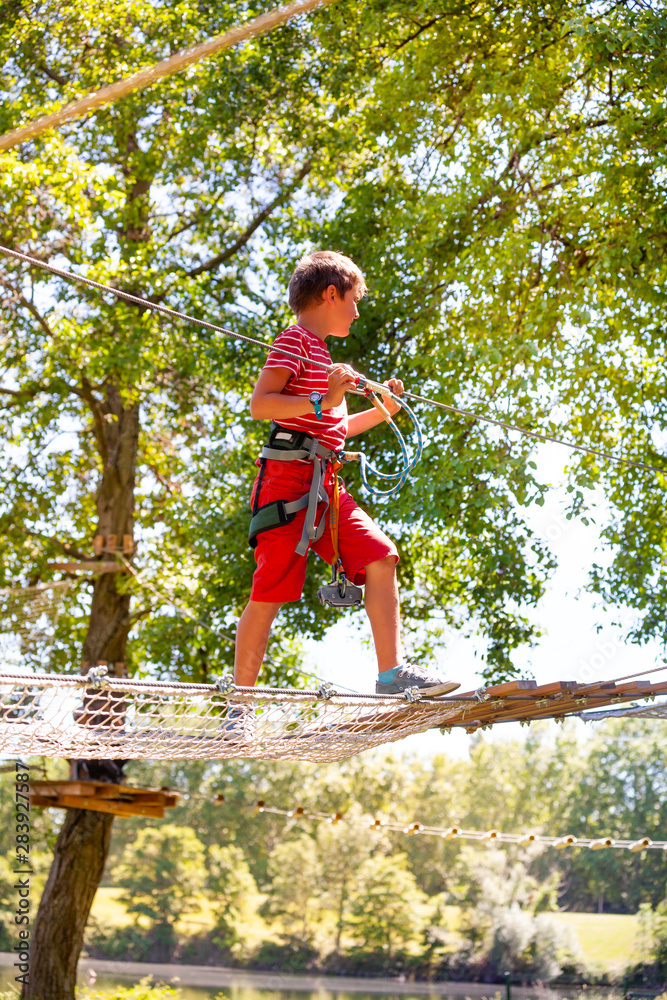 Boy walk over net between trees at rope park