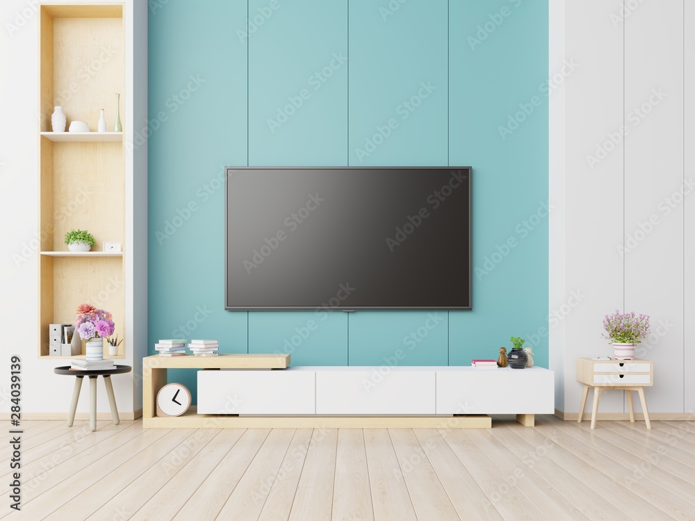 现代客厅橱柜上的电视有植物，蓝色墙壁背景上有书。
