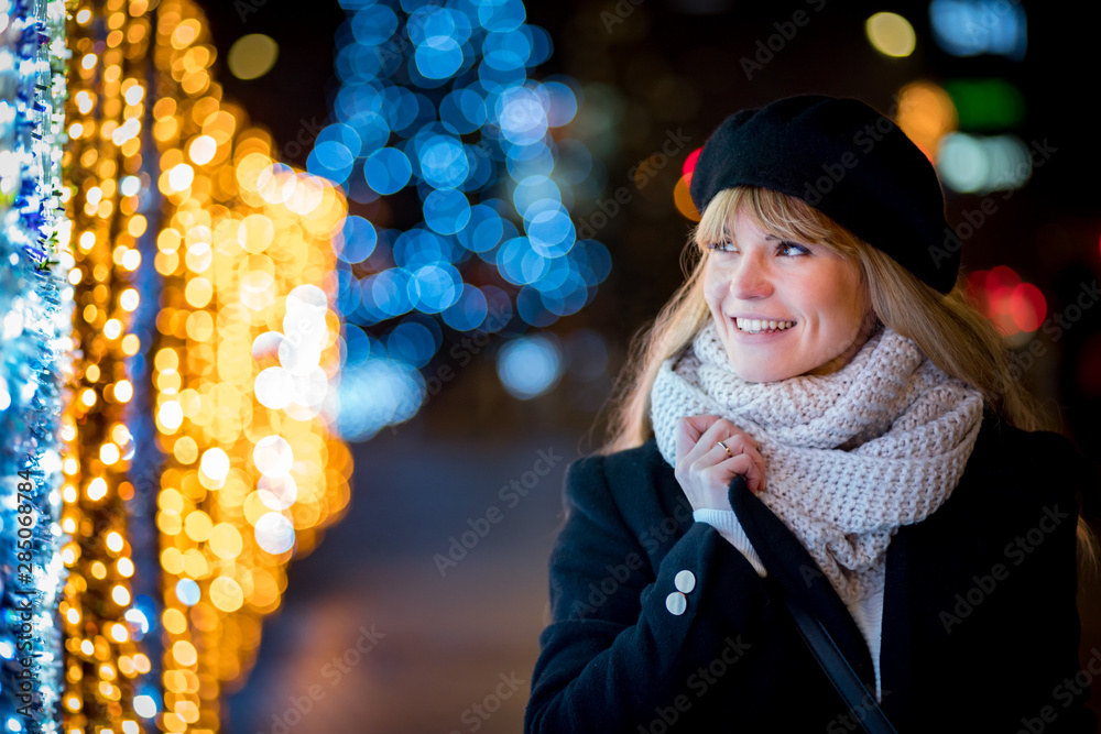 快乐的微笑女孩在圣诞期间沿着照亮的小巷散步